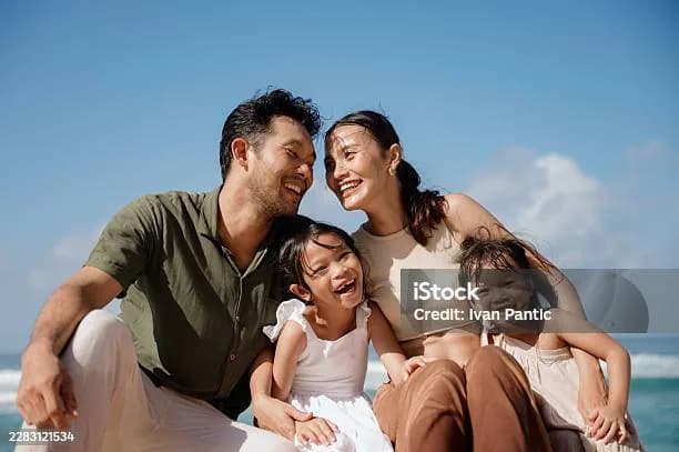 Parents laughing with their two young daughters on a sunny beach