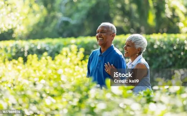 An older couple laughing together on a walk through a sunny garden